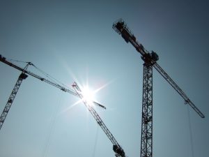 Baukräne vor blauem Himmel mit Sonne